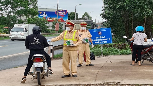 Người đi xe m&ocirc; t&ocirc; nhận khẩu trang miễn ph&iacute; từ cảnh s&aacute;t giao th&ocirc;ng.