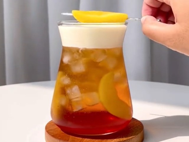 Trà ô long quế hoa kem cheese là sự giao thoa độc đáo giữa lớp kem béo mặn, vị trà thanh tao và những miếng đào mọng nước tạo nên một hành trình vị giác đầy bất ngờ và cuốn hút.