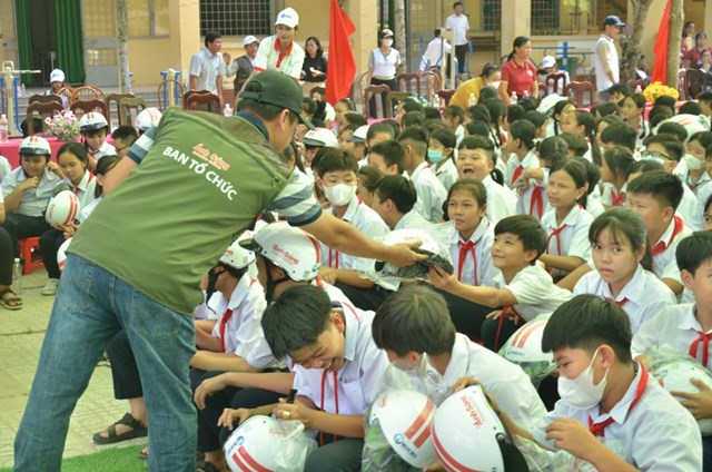 C&aacute;c th&agrave;nh vi&ecirc;n đo&agrave;n &ldquo;&Aacute;nh s&aacute;ng học đường&rdquo; tặng mũ bảo hiểm cho c&aacute;c em học sinh