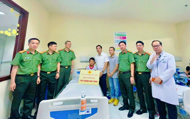 Thiếu tướng Trần Văn Ph&uacute;c - Ủy vi&ecirc;n Ban Thường vụ Tỉnh ủy, B&iacute; thư Đảng ủy, Gi&aacute;m đốc C&ocirc;ng an tỉnh (&aacute;o trắng, b&ecirc;n phải cạnh ch&aacute;u b&eacute;) c&ugrave;ng tập thể l&atilde;nh đạo c&aacute;c ph&ograve;ng nghiệp vụ trao số tiền hỗ trợ 200 triệu đồng v&agrave; nhận đỡ đầu ch&aacute;u Ho&agrave;ng Nhật Minh.