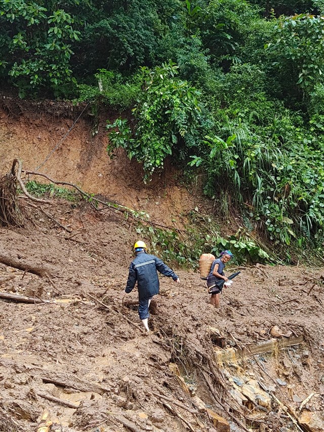 C&ocirc;ng nh&acirc;n Điện lực tại Sơn La hỗ trợ người d&acirc;n qua khu vực sạt lở.