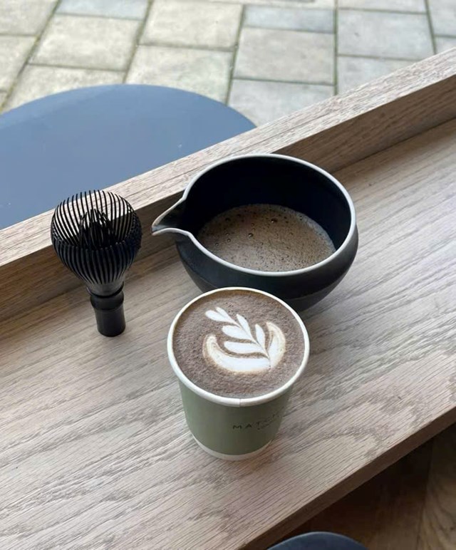 Một ly hojicha latte bên cạnh bát và dụng cụ đánh trà tại Matchado, quán cà phê mang phong cách Nhật ở phía Bắc London