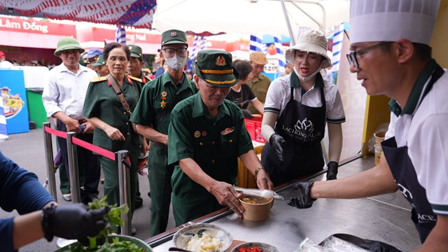 Cựu chiến binh nữ trong m&agrave;u &aacute;o xanh qu&acirc;n đội vui vẻ nhận phần b&aacute;nh đa cua n&oacute;ng hổi tại gian h&agrave;ng Hải Ph&ograve;ng.