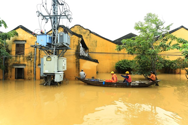 C&ocirc;ng nh&acirc;n điện lực thuộc EVNCPC vượt d&ograve;ng nước lũ để kh&ocirc;i phục lưới điện sau mưa b&atilde;o.