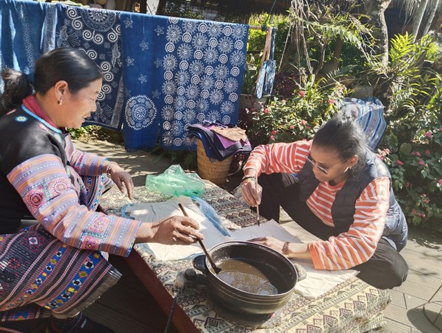 Du khách nước ngoài trải nghiệm vẽ sáp ong trong dịp năm mới tại homestay A Chu. Ảnh: Nam Trứ.