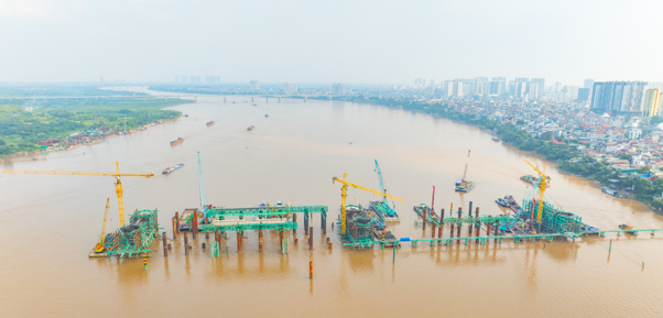 C&aacute;c trụ cầu ch&iacute;nh đang vươn l&ecirc;n giữa s&ocirc;ng Hồng, đ&aacute;nh dấu bước chuyển từ thi c&ocirc;ng nền m&oacute;ng sang ho&agrave;n thiện kết cấu cầu.